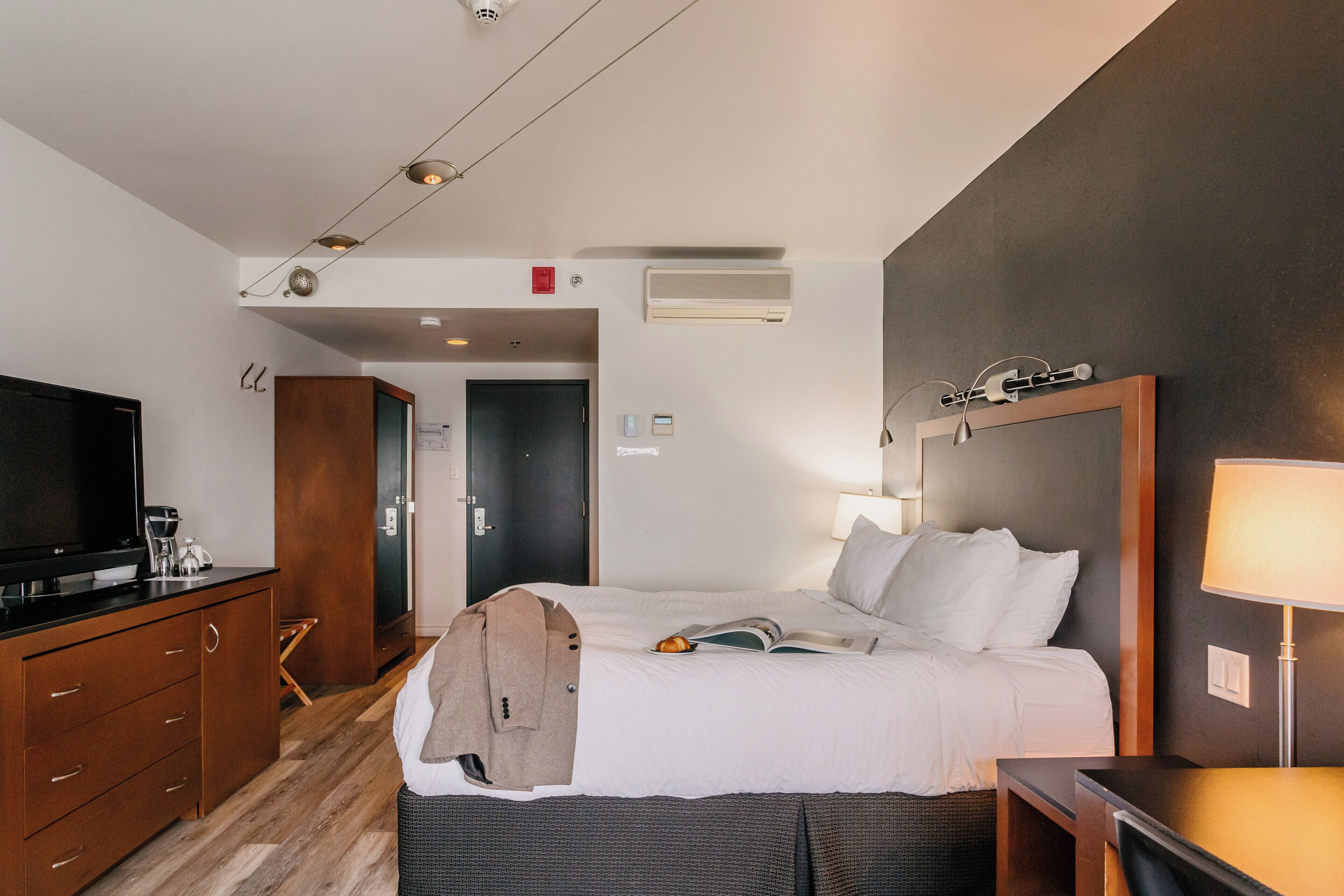 Een hotelkamer met een bed, een televisie, een bureau en een lamp.