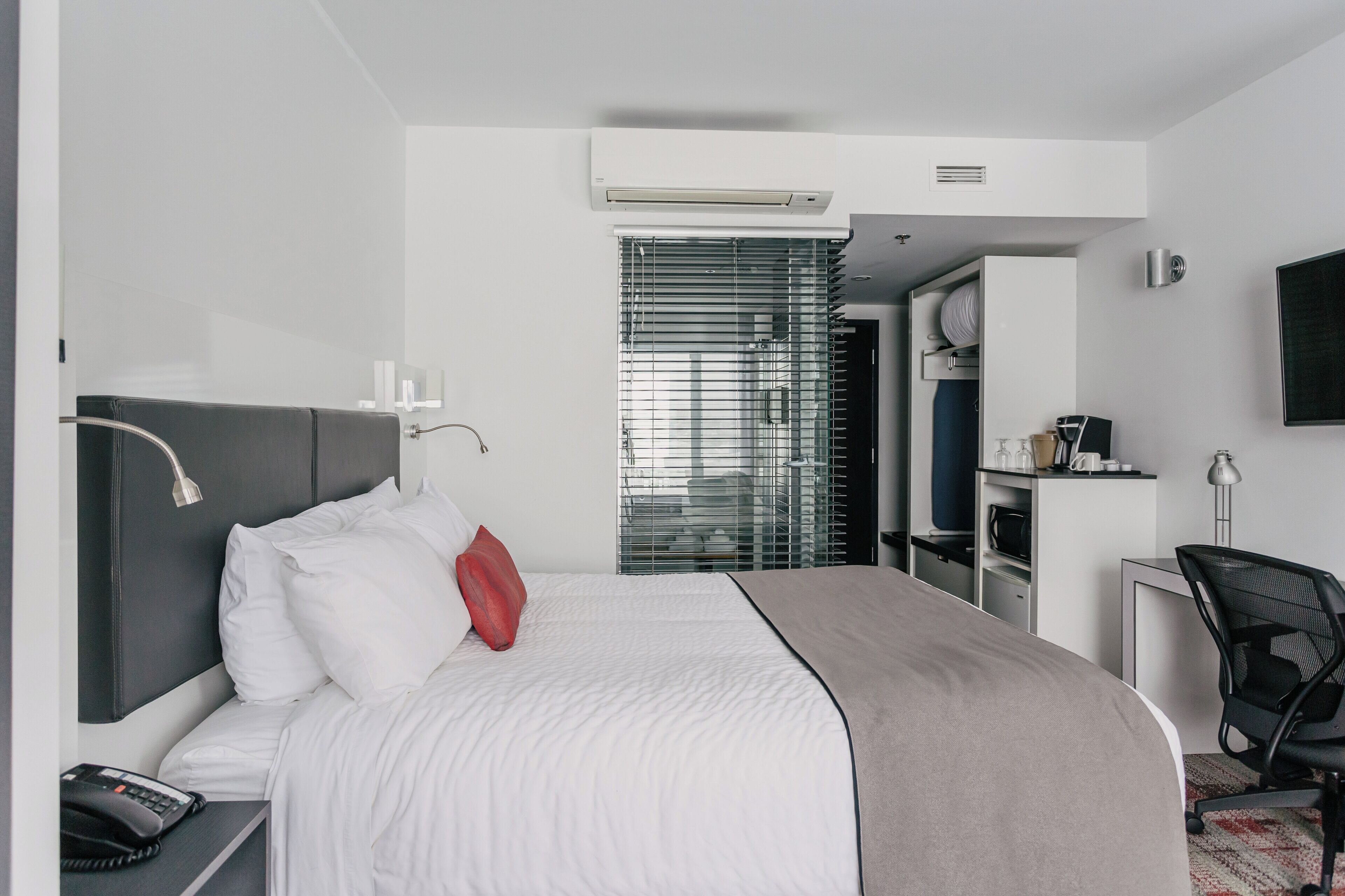 Una habitación de hotel moderna con cama, teléfono junto a la cama y escritorio con silla.