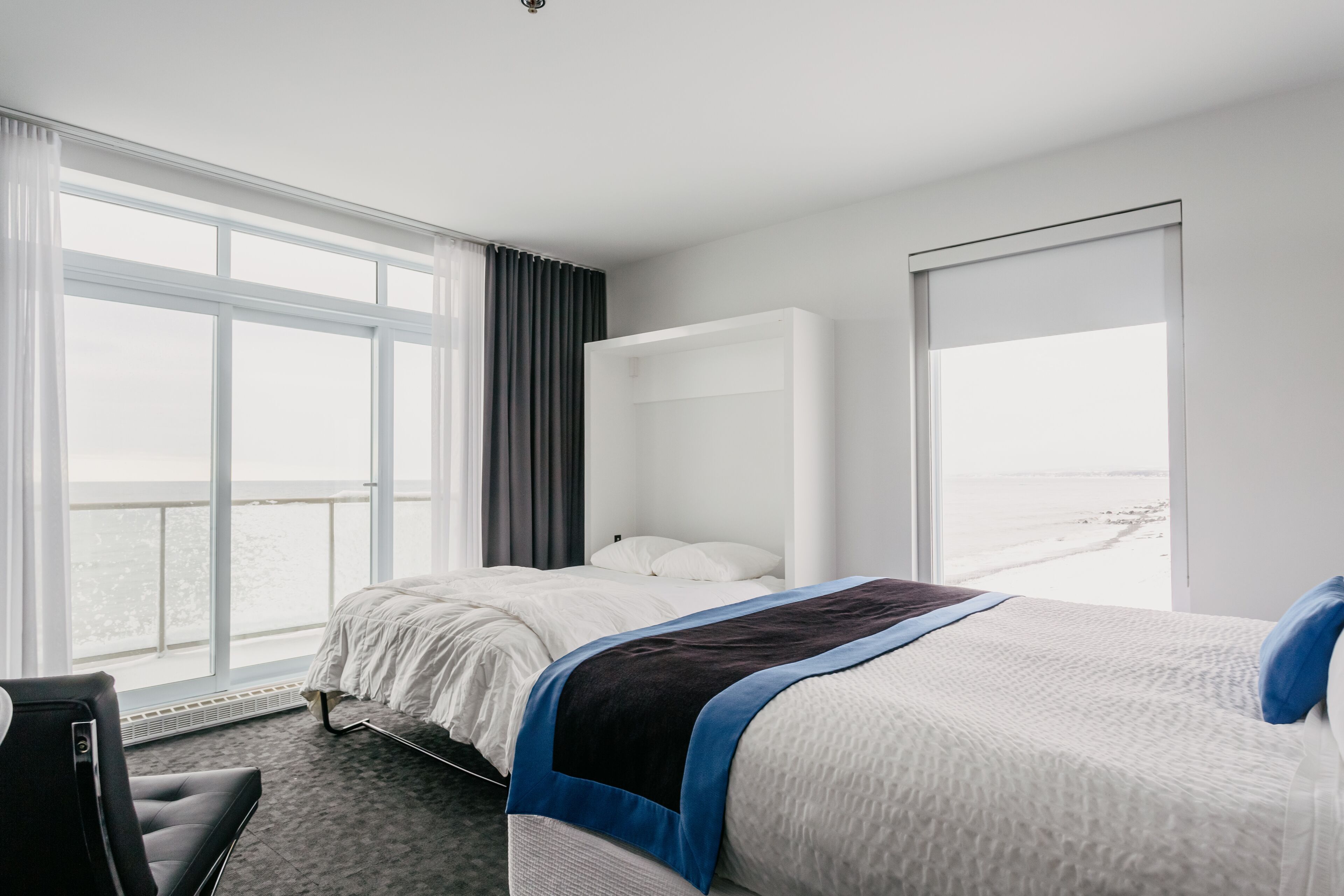 Een hotelkamer met een bed, een bureau en een groot raam met uitzicht op zee.