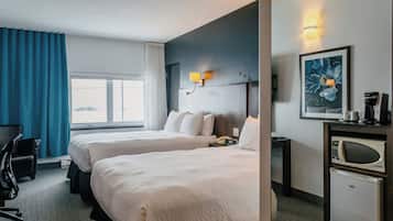 A hotel room with two beds, a desk, a chair, a microwave, and a coffee maker.