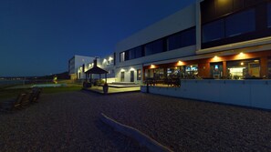 A modern building with a pool, outdoor seating, and a covered area.