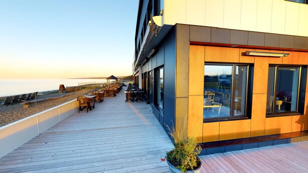 A wooden deck with outdoor seating overlooking a beach. - Riotel Matane (Matane)