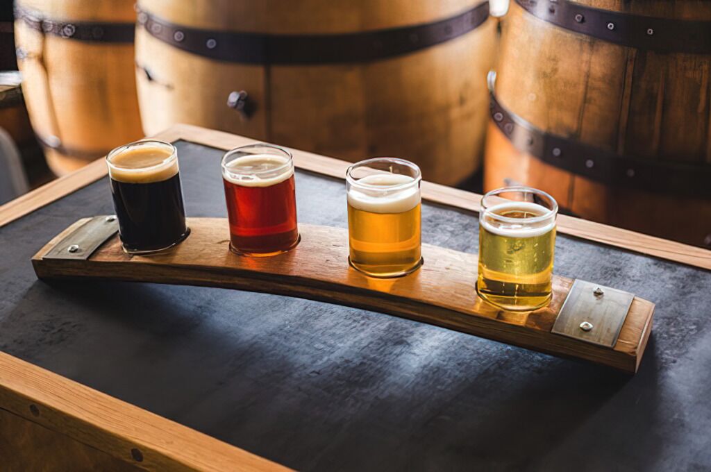 Four glasses of beer on a wooden tray.
