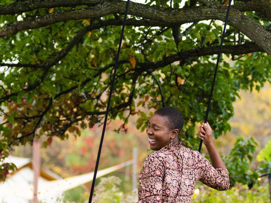 Une personne assise sur une balançoire, sous un arbre.