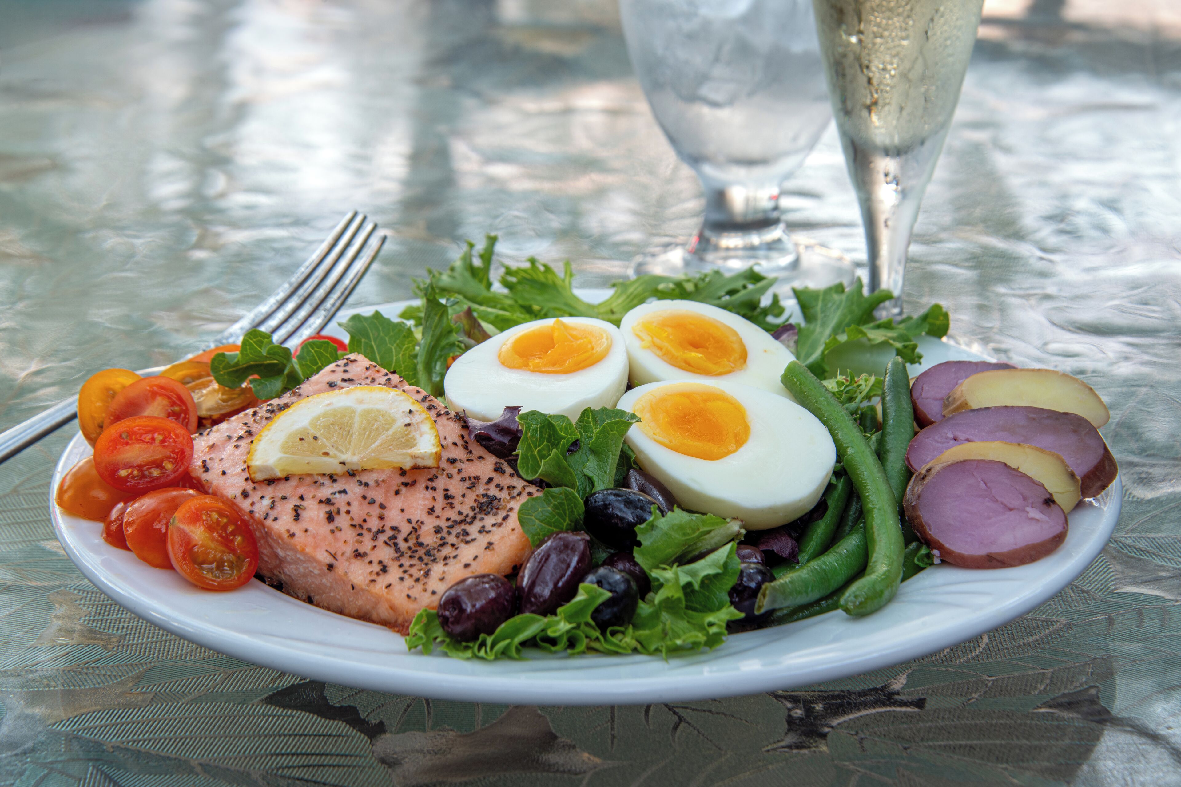 A plate of food with salmon, eggs, tomatoes, and green beans on a table.