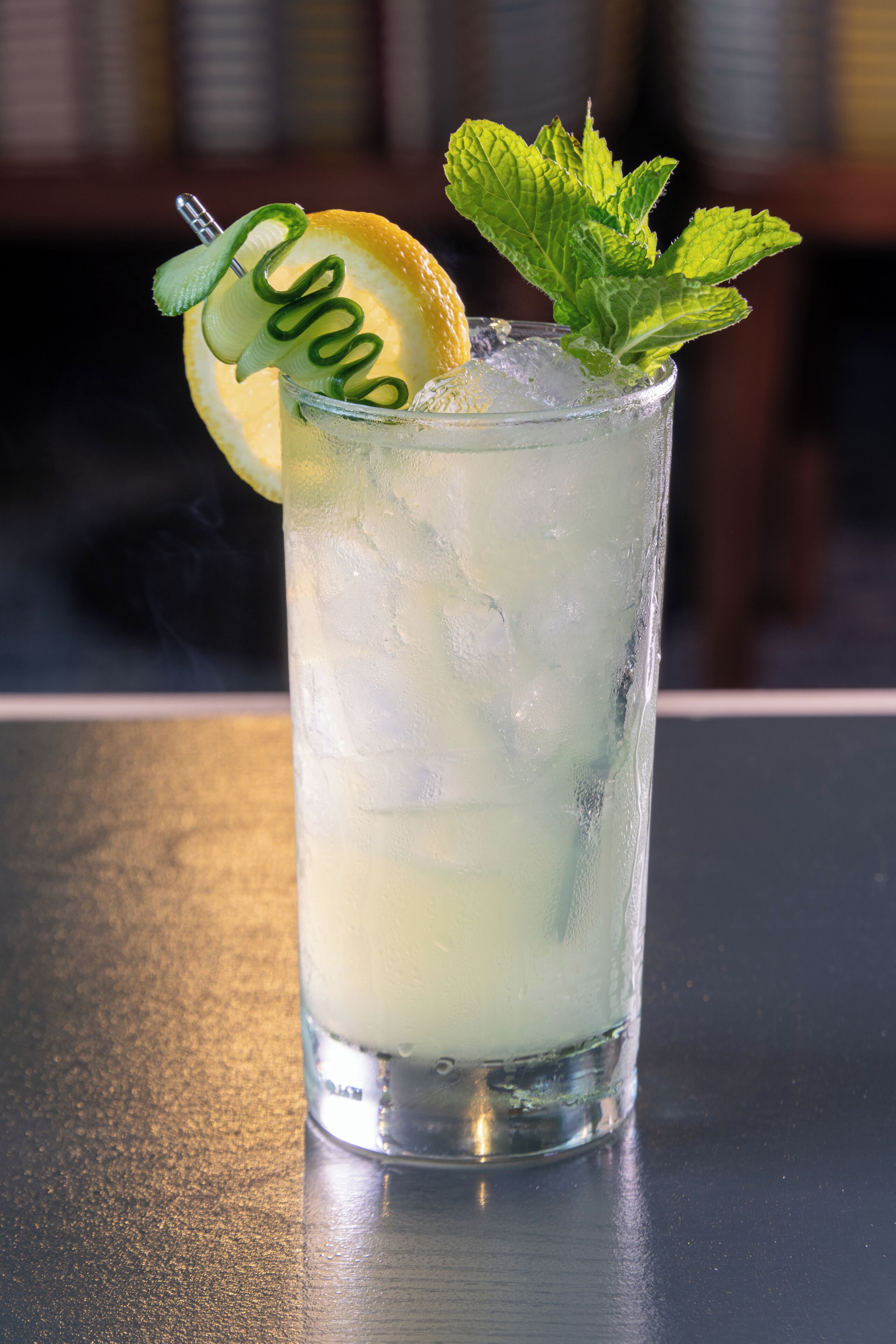 A tall glass with a lime slice and mint garnish, filled with a clear liquid and ice cubes.
