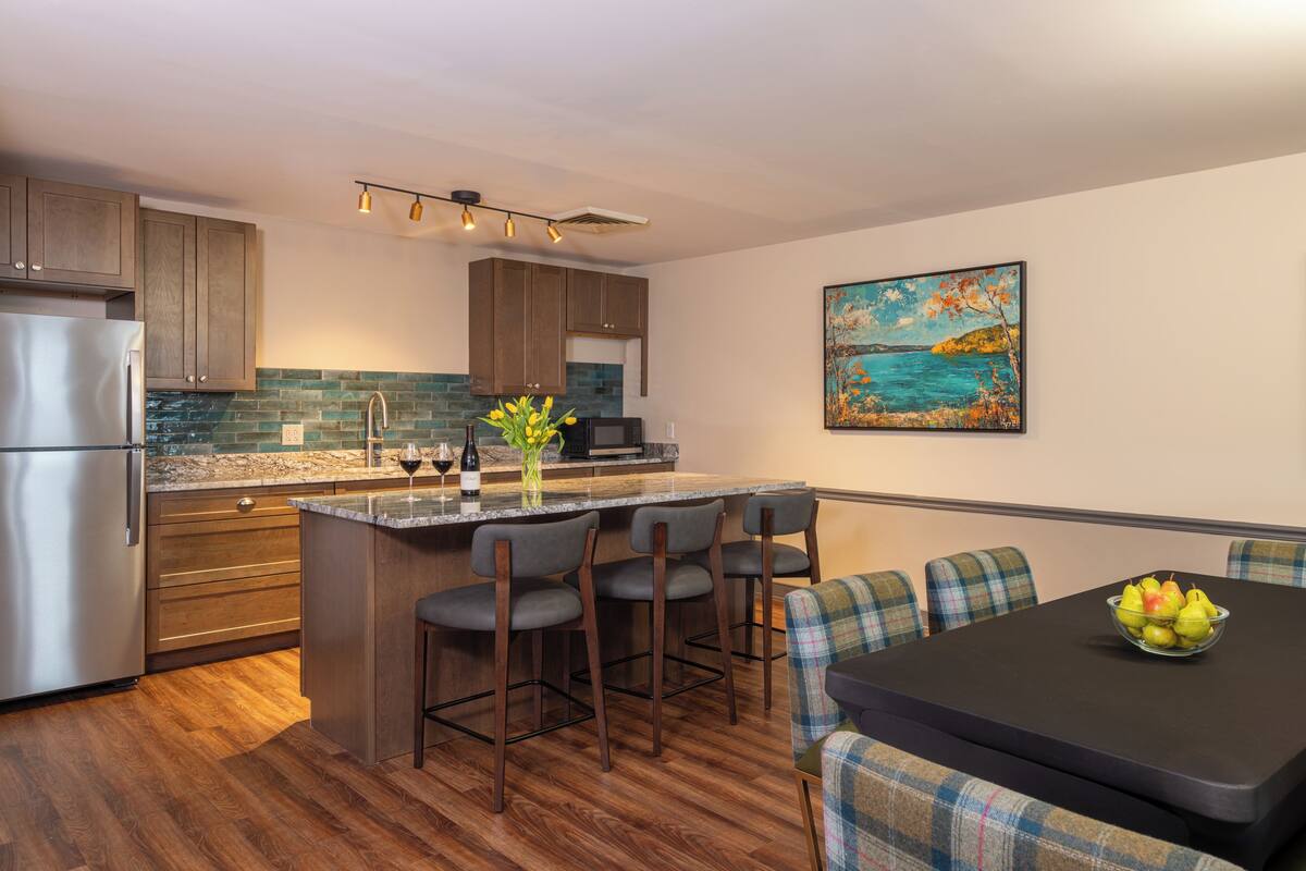 A modern kitchen with wooden cabinets, a granite countertop, and a central island with bar stools.