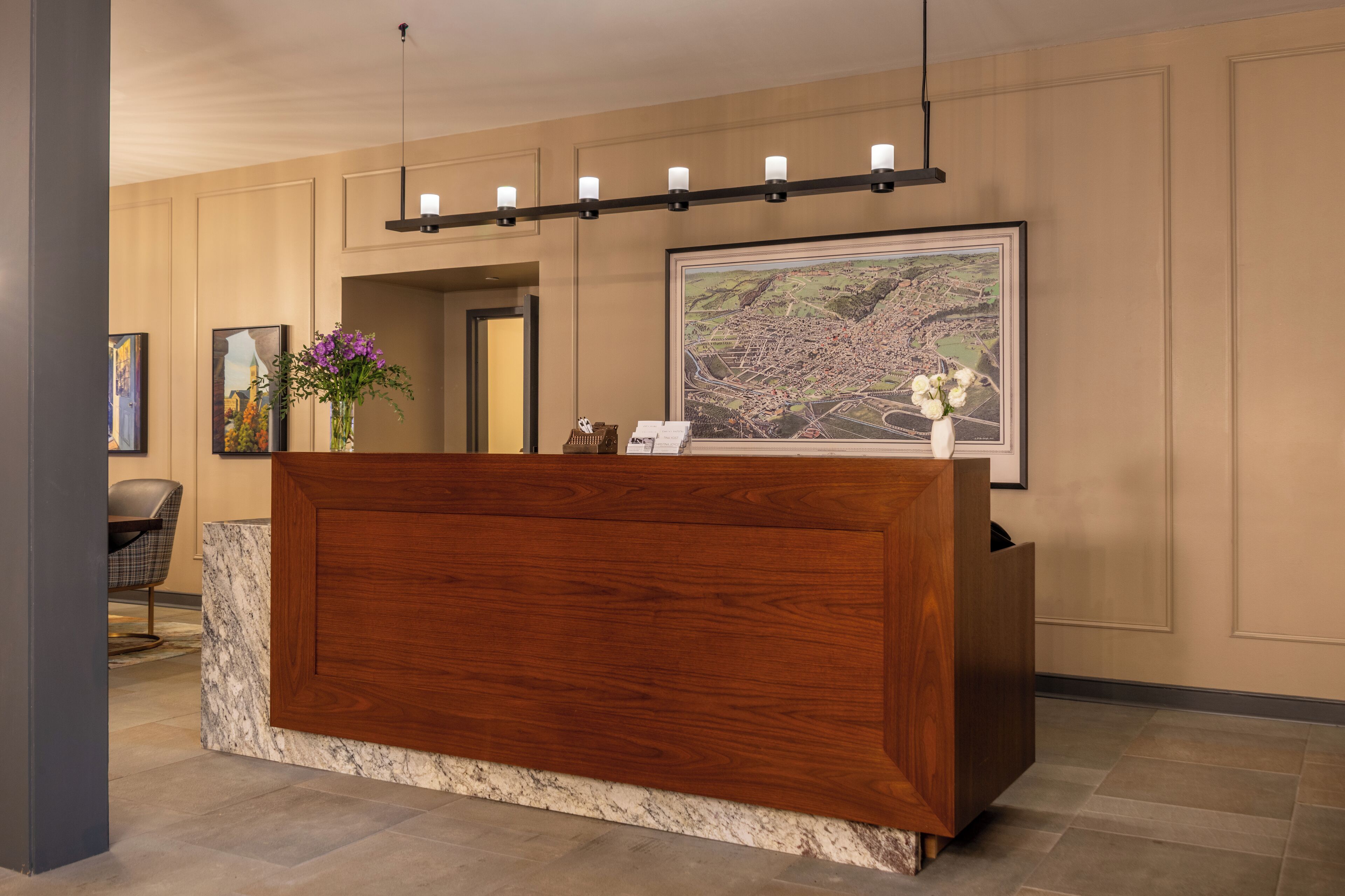 A reception desk with a wooden finish, a marble countertop, and a framed map on the wall.