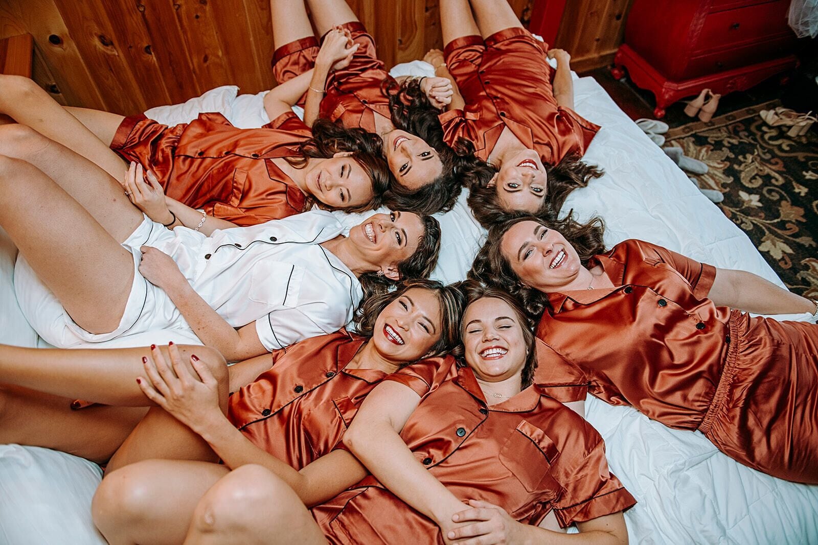 A group of people lying on a bed in matching red pajamas.