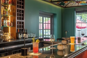 A bar area with a variety of drinks, a selection of bottles, and a view of the outdoors through large windows.