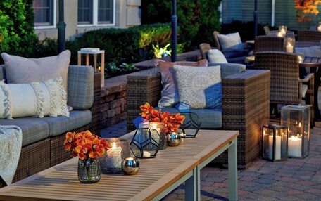 An outdoor seating area with wicker furniture, cushions, and candles.