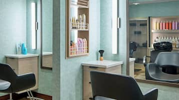 A salon with a teal wall, a mirror, a sink, and two chairs.
