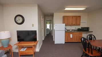A compact living space with a kitchenette, a dining area, and a TV.