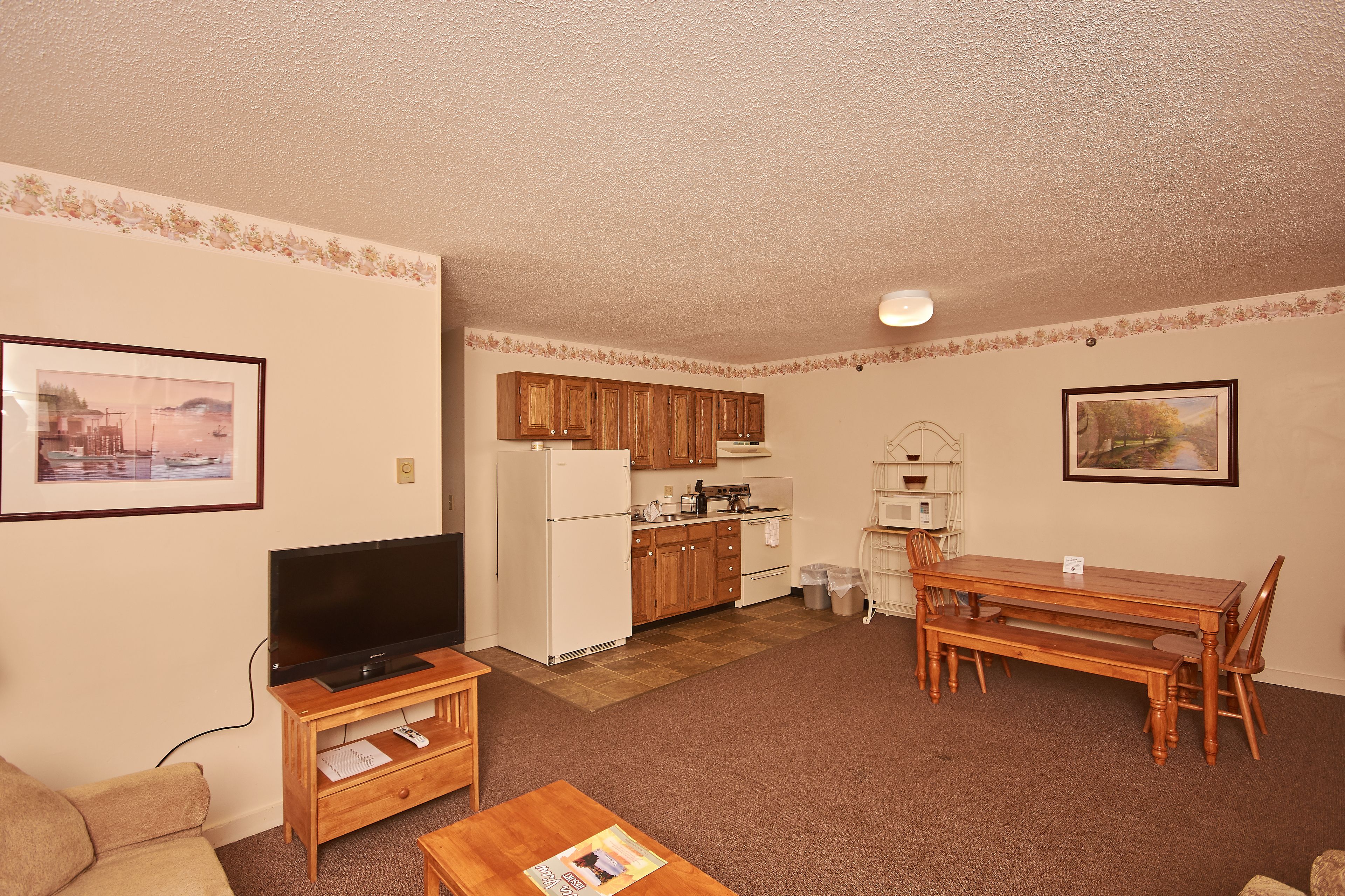 A compact living space with a kitchenette, a dining area, a television, and a sofa.
