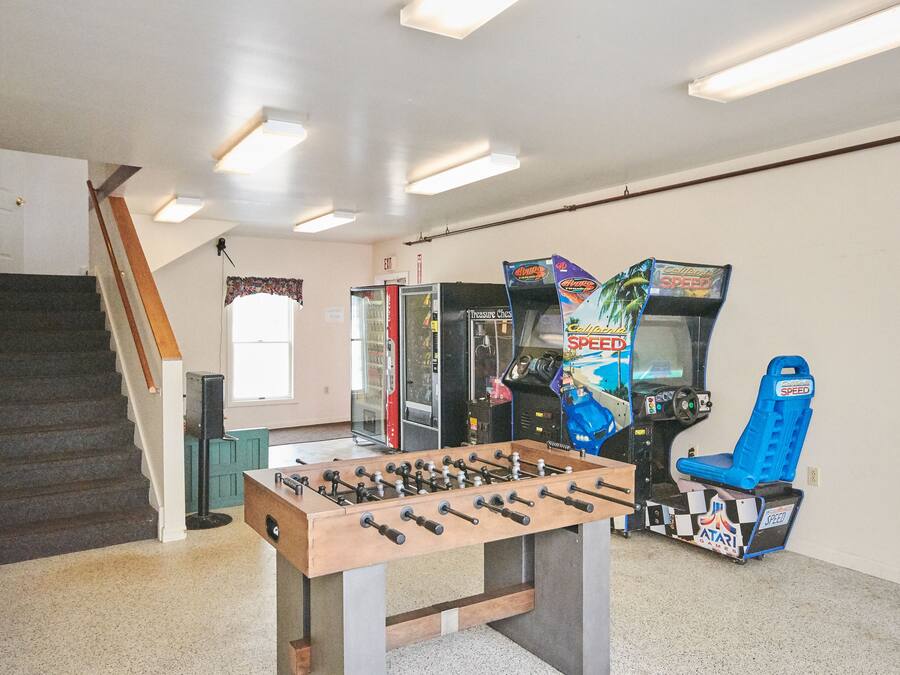 Una habitación con una mesa de fútbol de mesa, una escalera y juegos de arcade, incluyendo un juego llamado 'Speed'.