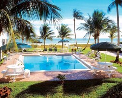 Una piscina al aire libre, sombrillas, sillones reclinables de piscina