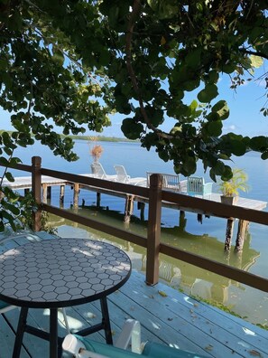 A wooden deck with a hexagonal table and chairs overlooking a calm lake.