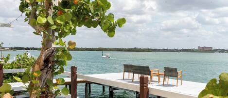 A wooden deck with chairs and a table overlooking a body of water.