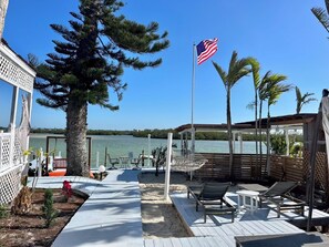 A deck with outdoor seating, a view of a body of water, and a flag.