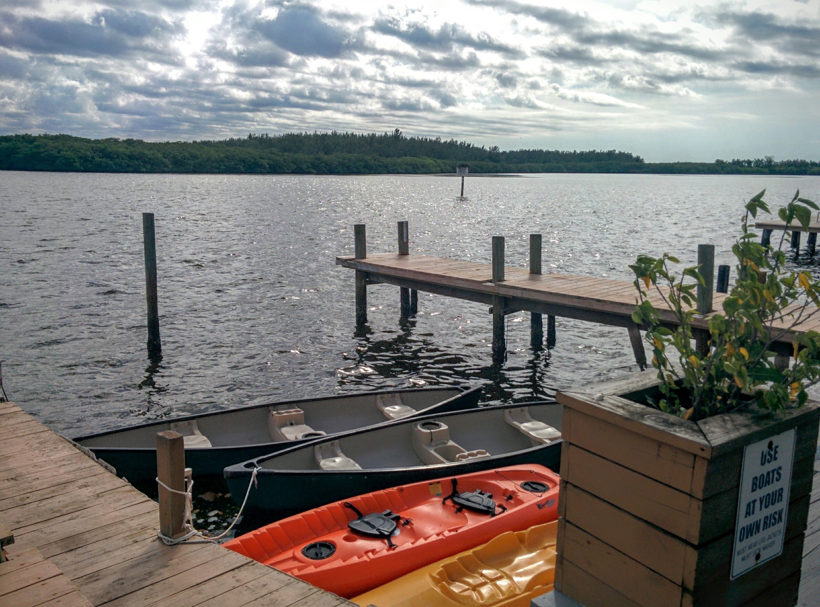 Un quai avec une jetée en bois qui s’avance dans un lac, le tout entouré de verdure.