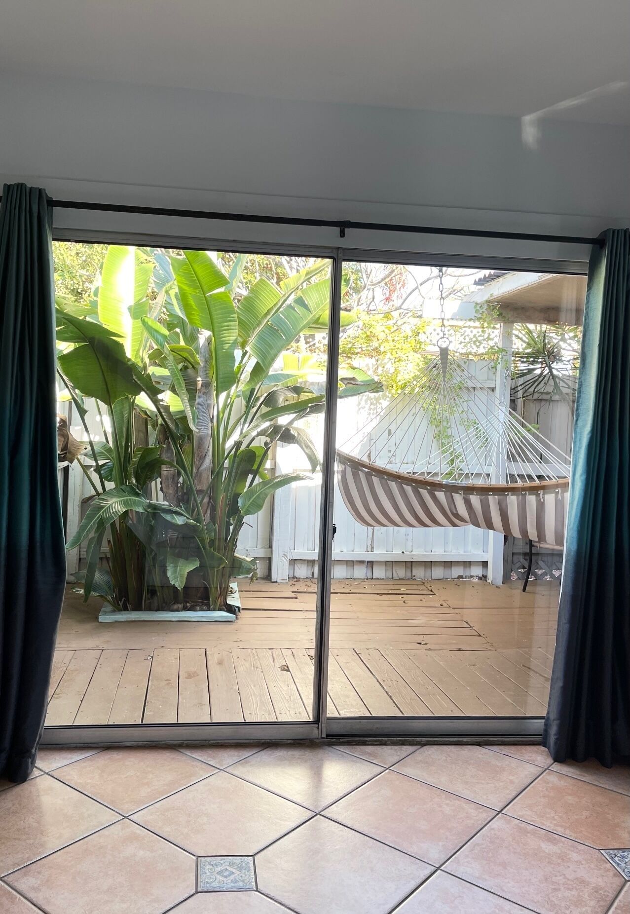 A sliding glass door leading to an outdoor patio with a hammock and large green plants.