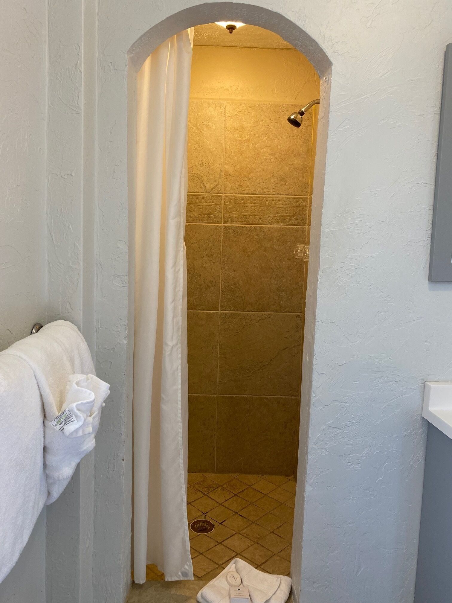 Une salle de bain avec un espace douche, un porte-serviettes et un lavabo.