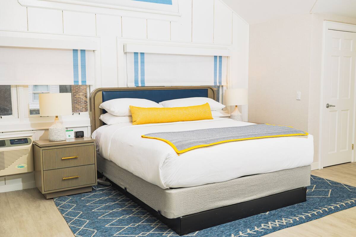 A neatly arranged bedroom with a bed, bedside tables, and a nightstand.