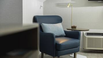 Een moderne kamer met een blauwe fauteuil, een klein rond tafeltje en een staande lamp.
