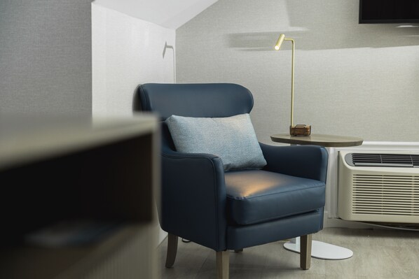 A modern room with a blue armchair, a small round table, and a standing lamp.