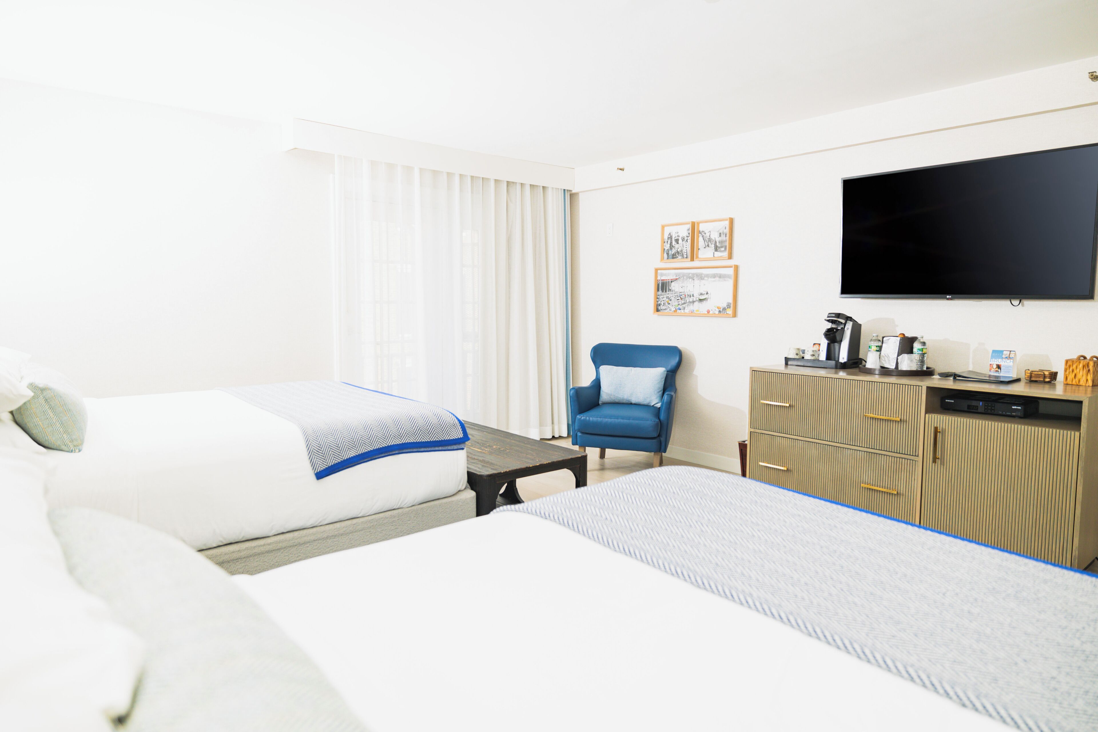 Une chambre d’hôtel avec deux lits, un bureau, une chaise, une télévision et un mini-bar.