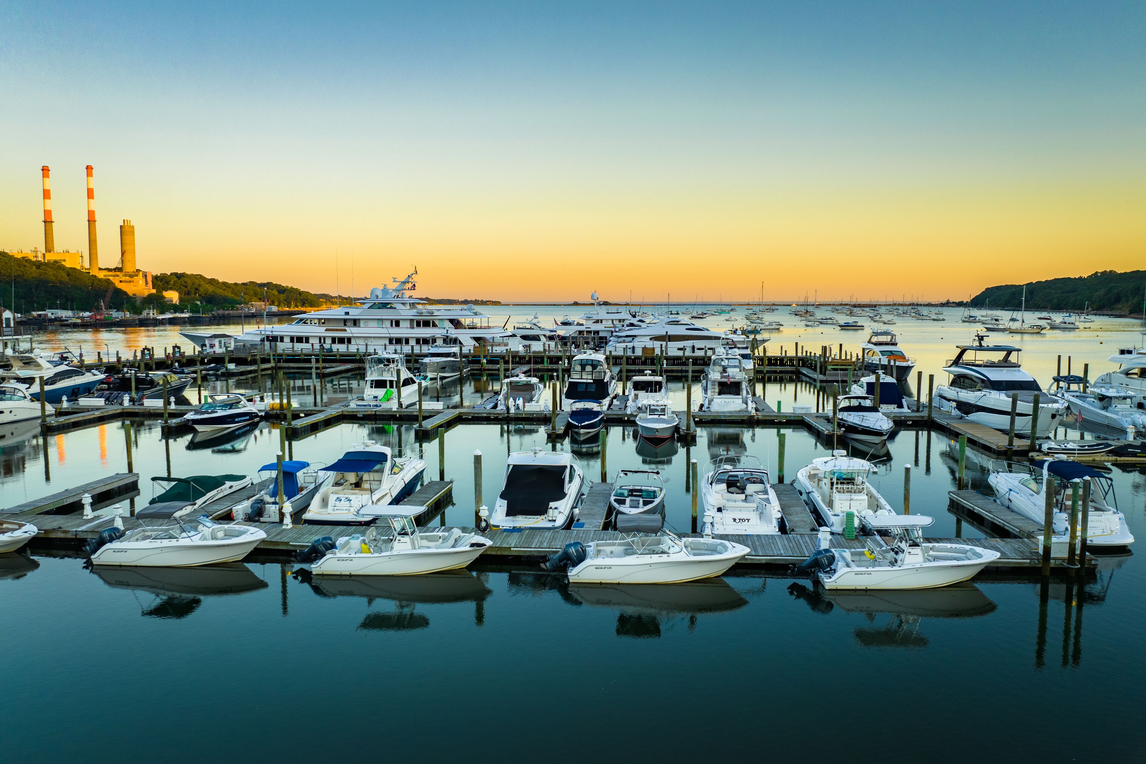Un port de plaisance où diverses embarcations sont amarrées aux quais, entouré d’une eau calme et sous un ciel dégagé.
