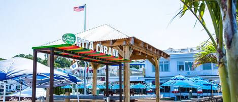 A beachside restaurant with outdoor seating and a sign reading "Rita Carana."