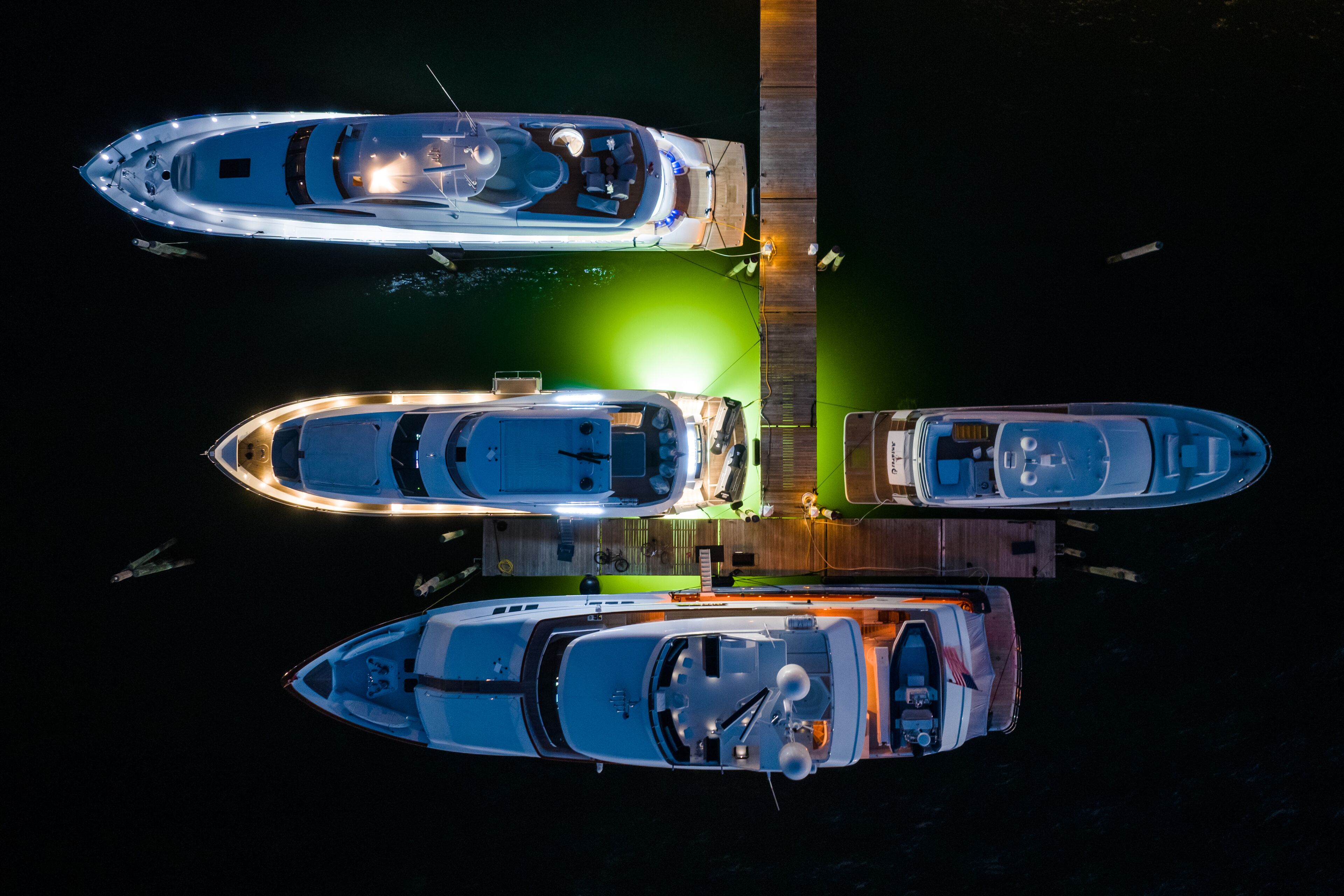 A marina with three boats docked at a wooden pier.