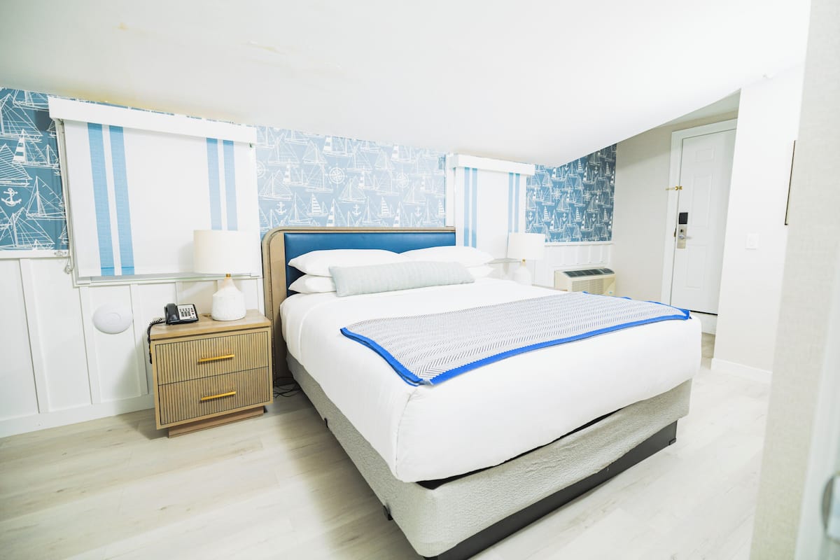 A neatly arranged bedroom with a bed, bedside tables, and a nightstand.