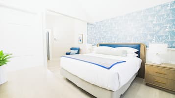 A modern hotel room with a large bed, a bedside table with a lamp, and a wall with nautical-themed wallpaper.