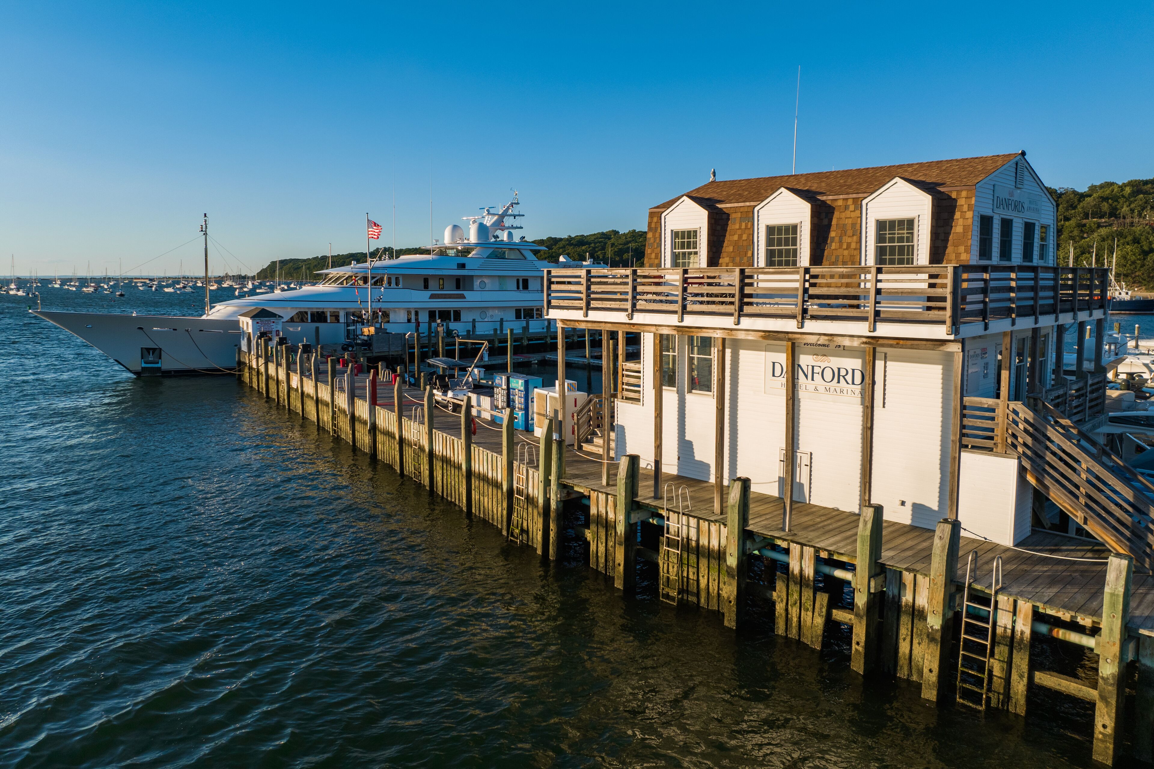 A waterfront dock with a white building labeled "DANFORD & MARINA" and a large yacht docked nearby.