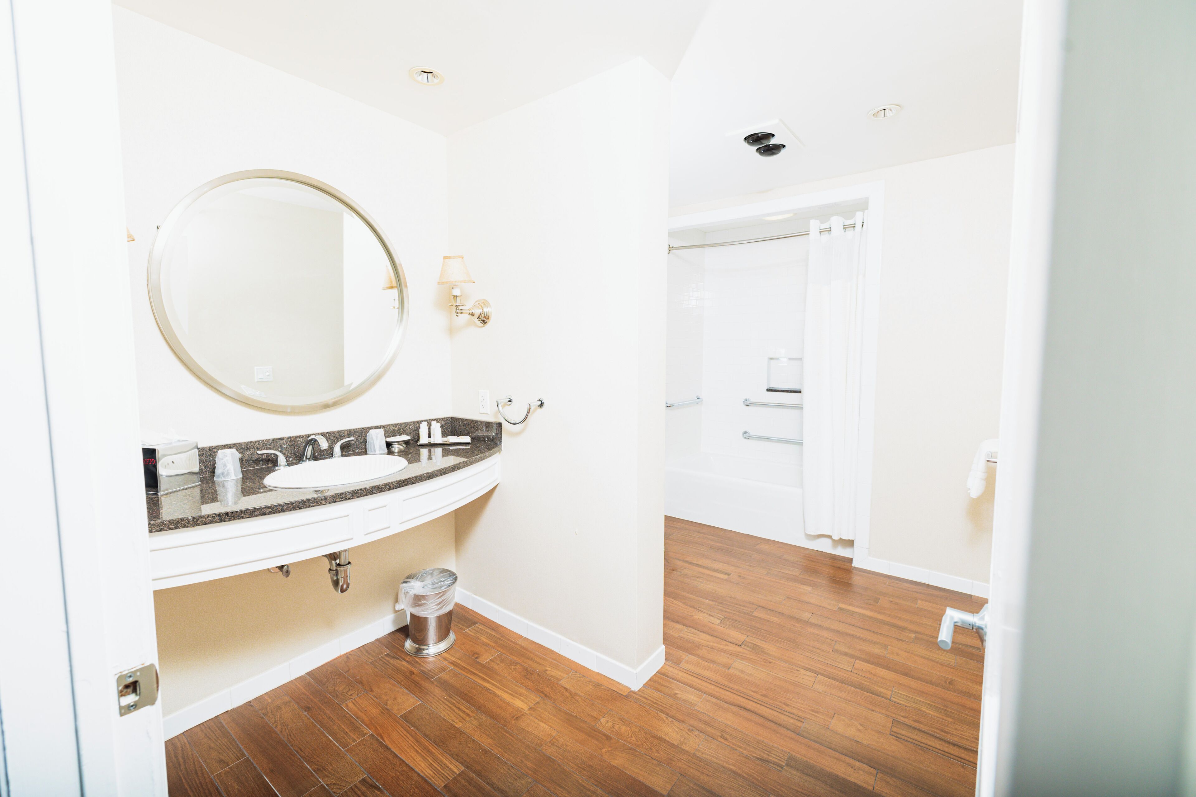 A bathroom with a white sink, a round mirror, and a shower area.