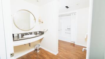 A bathroom with a white sink, a round mirror, and a shower area.