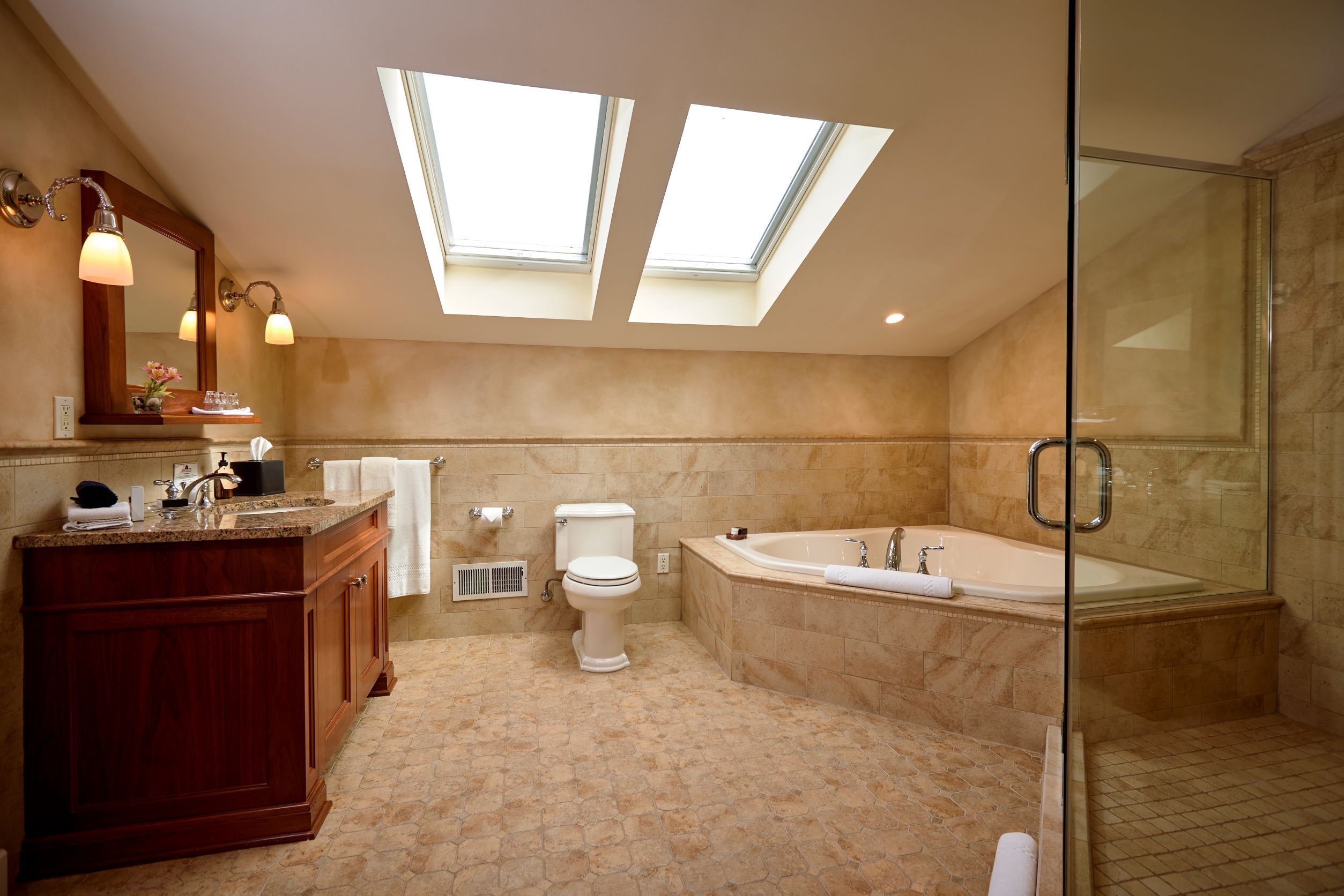 A modern bathroom with skylights, a freestanding bathtub, and a glass-enclosed shower.