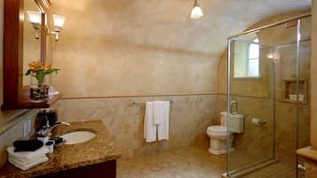 A bathroom with a granite countertop, a sink, a toilet, and a glass-enclosed shower.