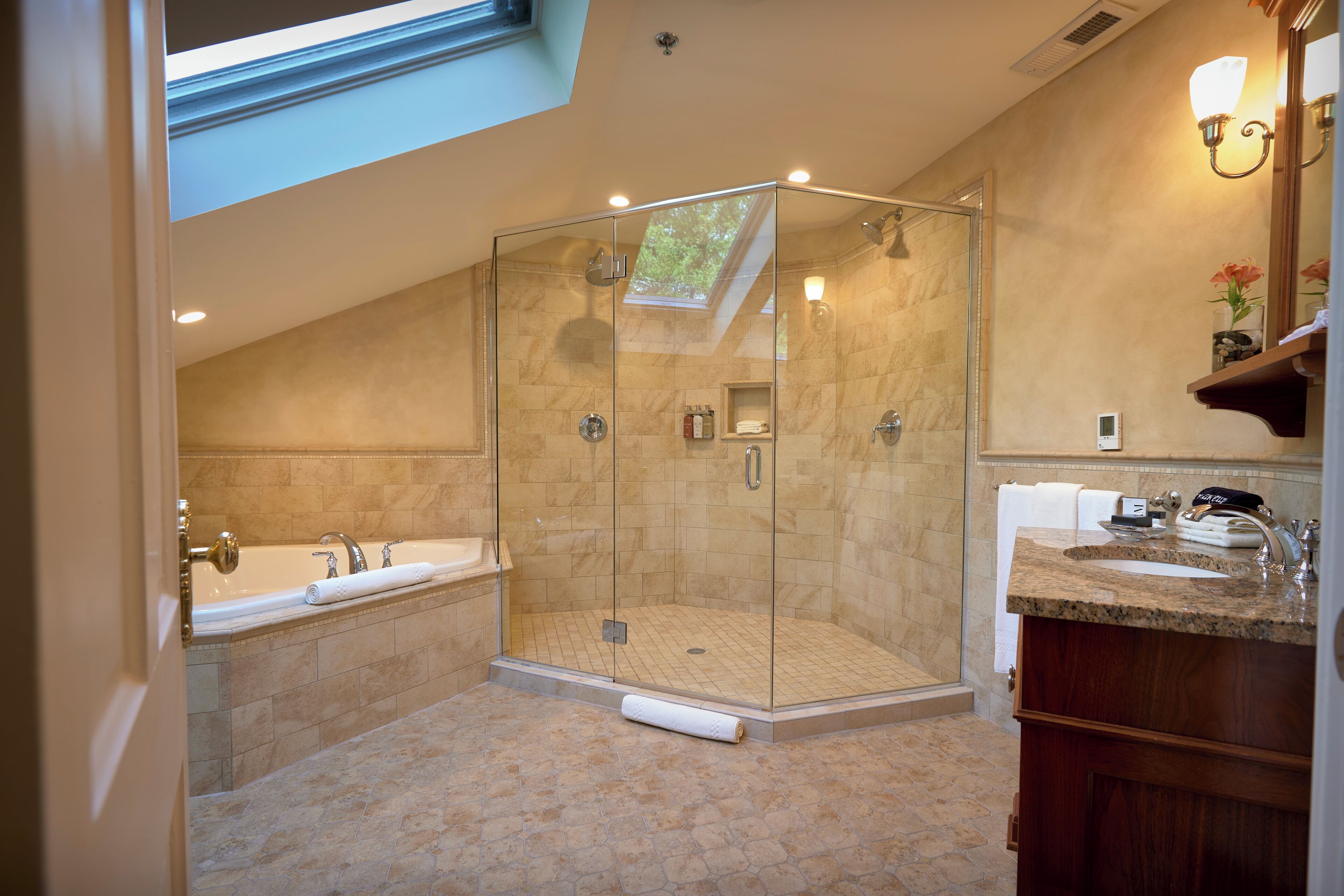A modern bathroom with a glass-enclosed shower, a freestanding bathtub, and a vanity with a sink and mirror.