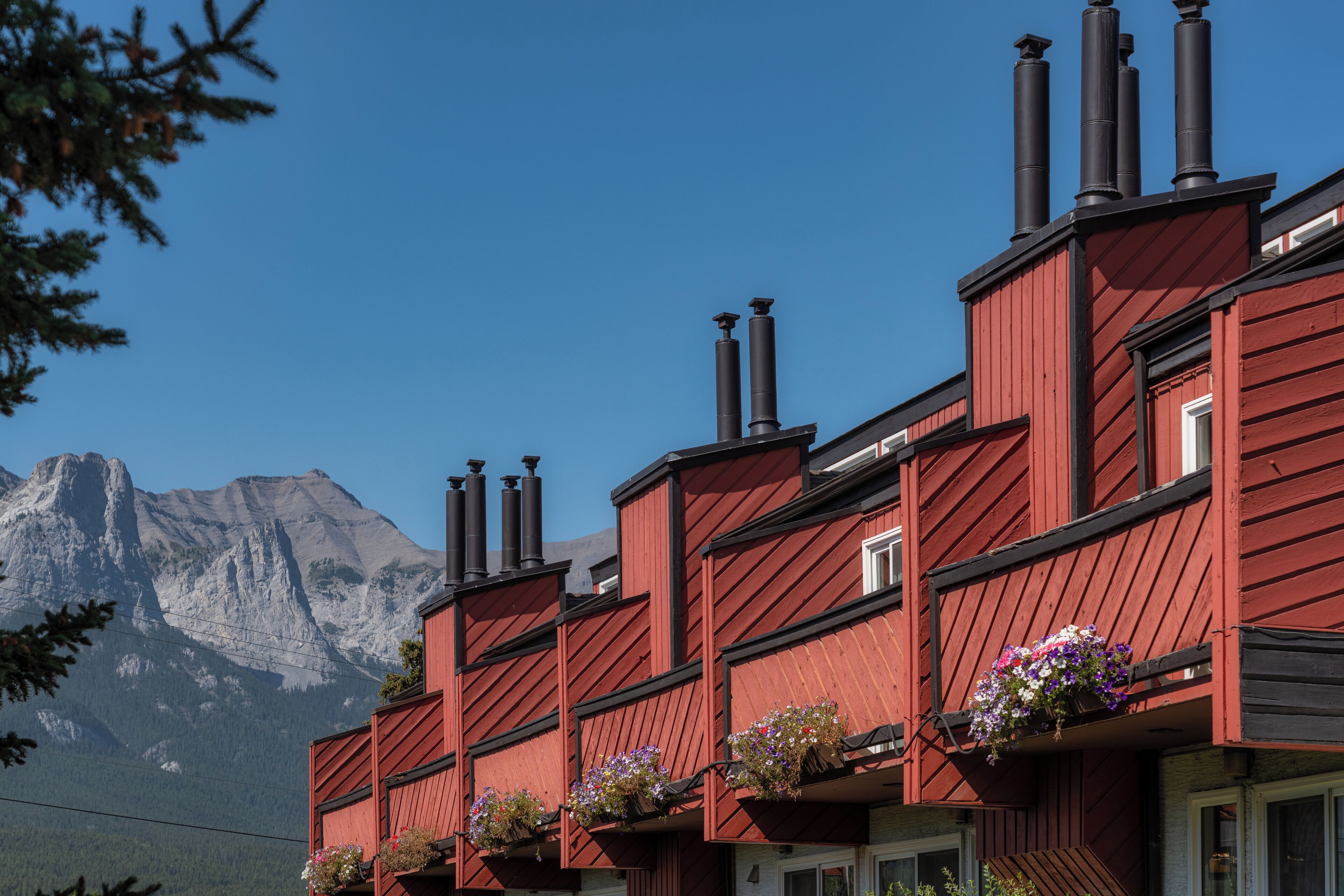 Um edifício vermelho com várias chaminés e caixas de flores na varanda.