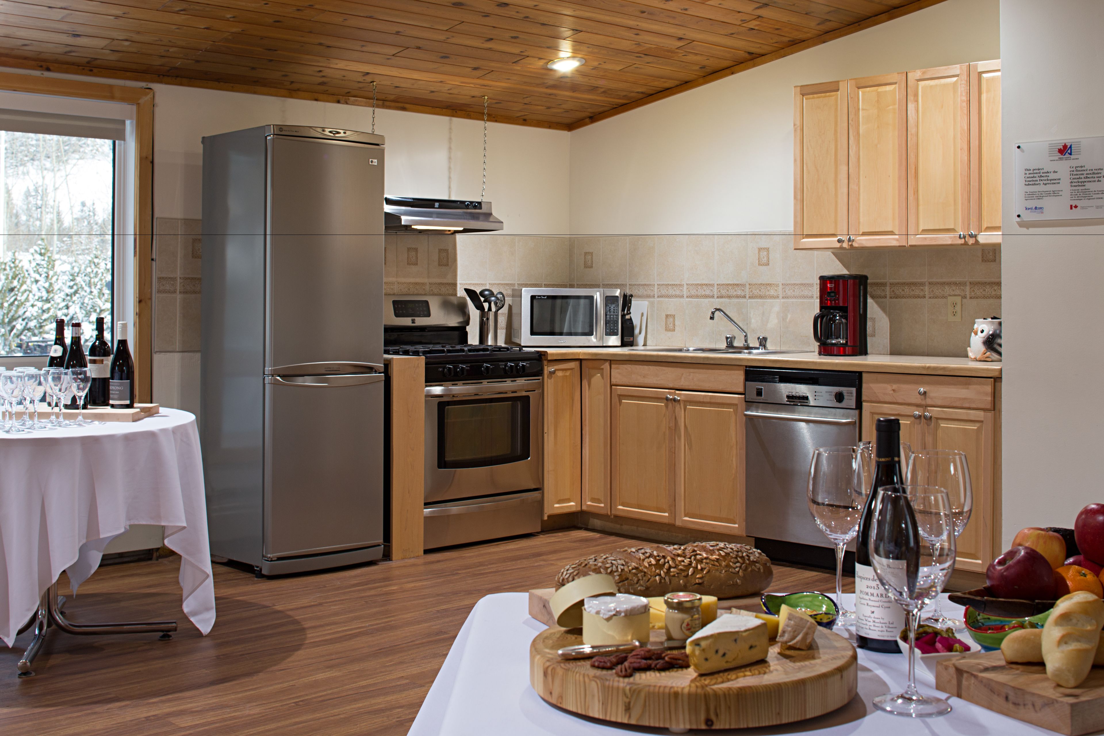 A modern kitchen with stainless steel appliances, wooden cabinets, and a dining area with a table set for a meal.