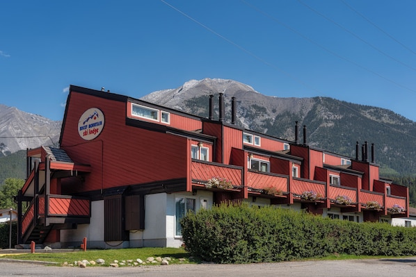 A red building with a ski lodge sign, multiple windows, and a mountain backdrop.