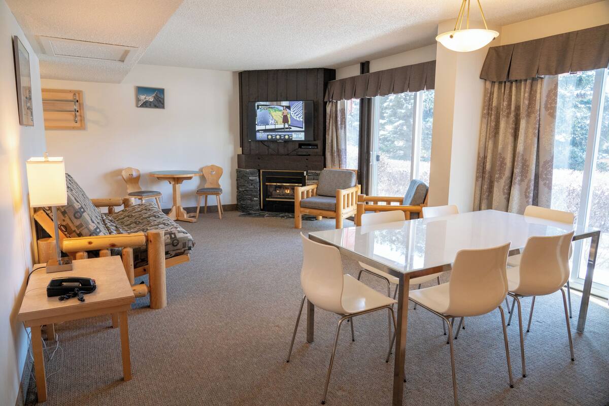 Una sala de estar acogedora con chimenea, televisor, mesa de comedor con sillas y sofá.