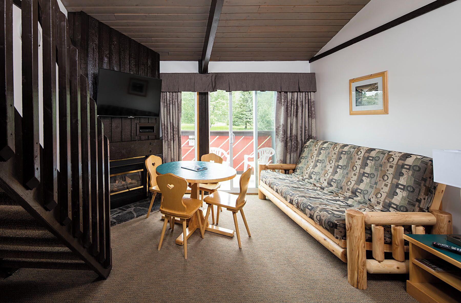 Un salón acogedor con sofá, mesa, sillas, chimenea y televisión.