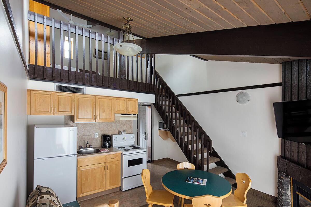Un espacio habitable tipo loft con cocina, comedor y escalera.