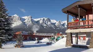 A snow-covered outdoor area with a wooden deck overlooking a mountain range. - Rocky Mountain Ski Lodge (Canmore)