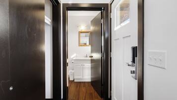 Pasillo que conduce a un baño con un lavamanos y un espejo blancos.