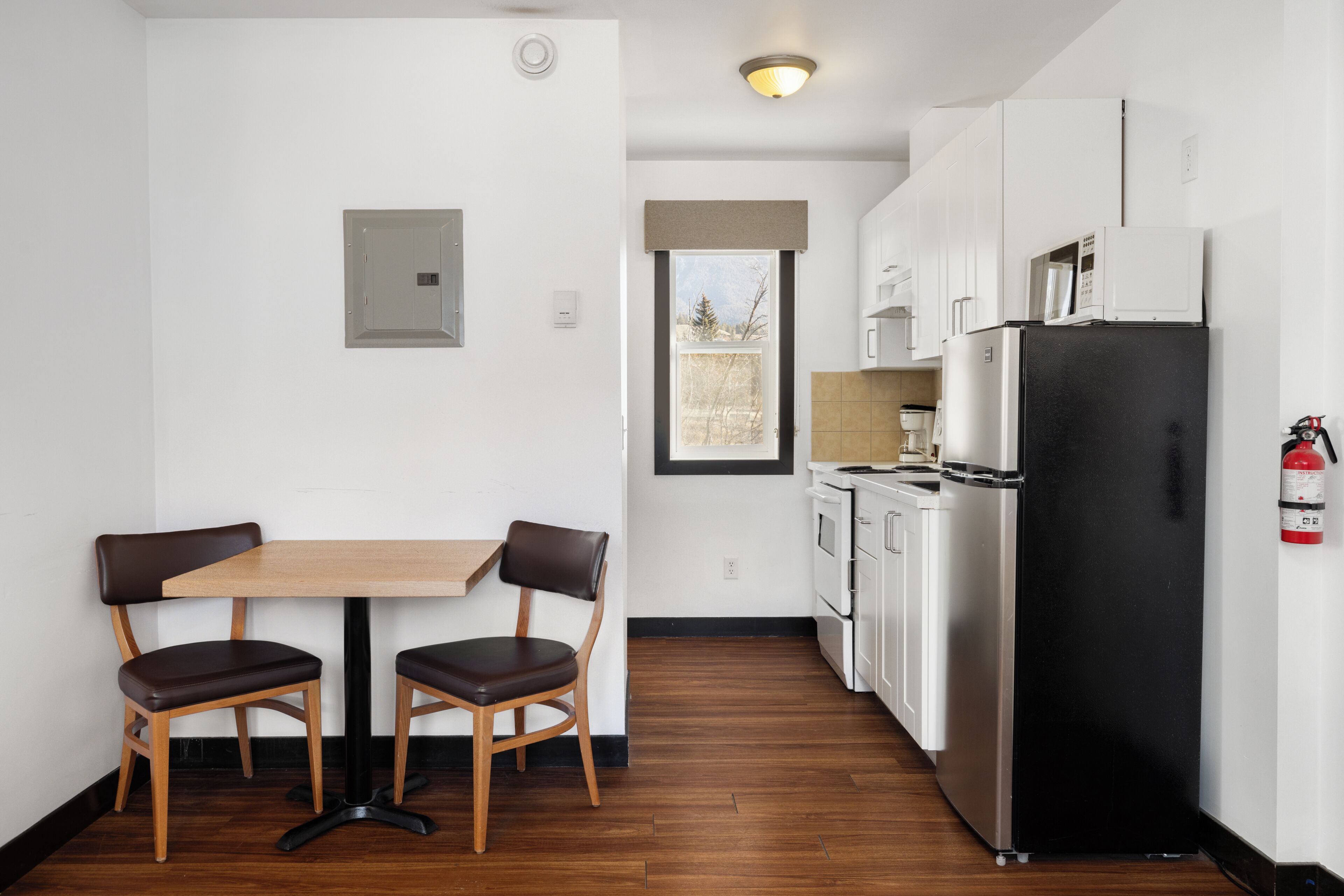 Cocina compacta con una mesa de comedor y sillas, un refrigerador y una ventana con vistas.